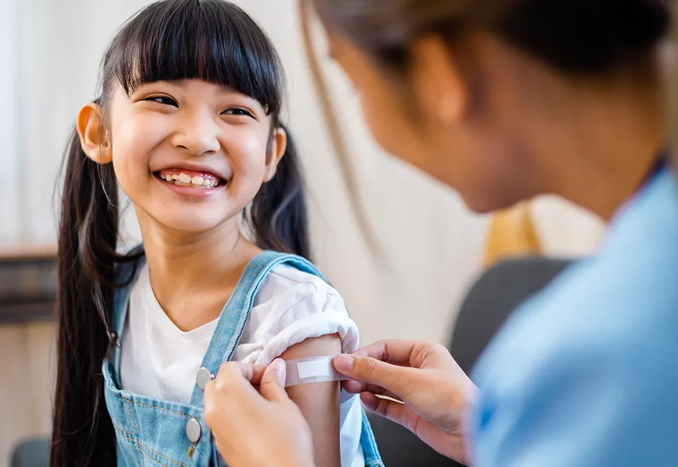 Happy Asian girl getting the flu vaccine from a doctor. 