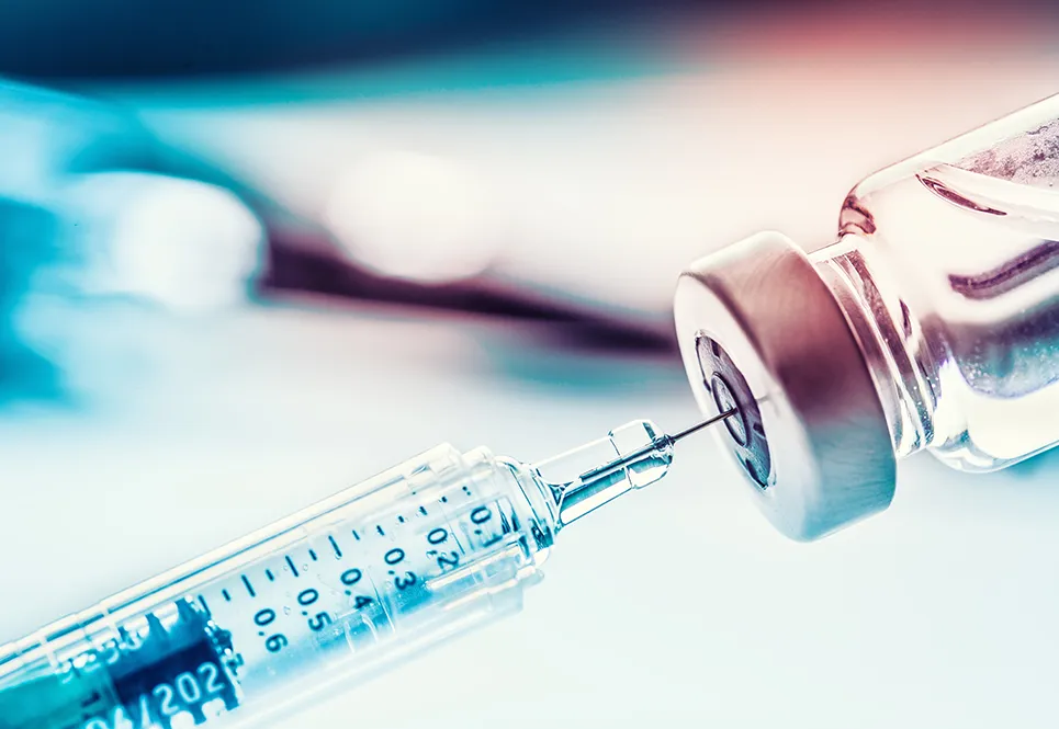 Closeup shot of a syringe extracting flu vaccine from a vial. 