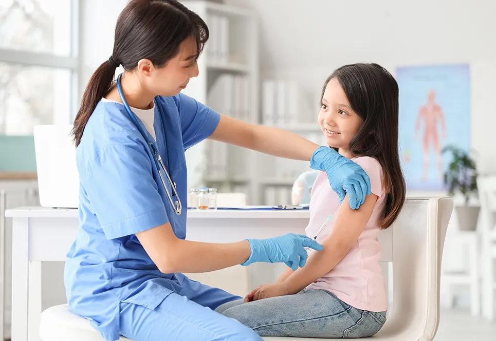 Happy looking pediatrician giving a vaccine to a young girl.