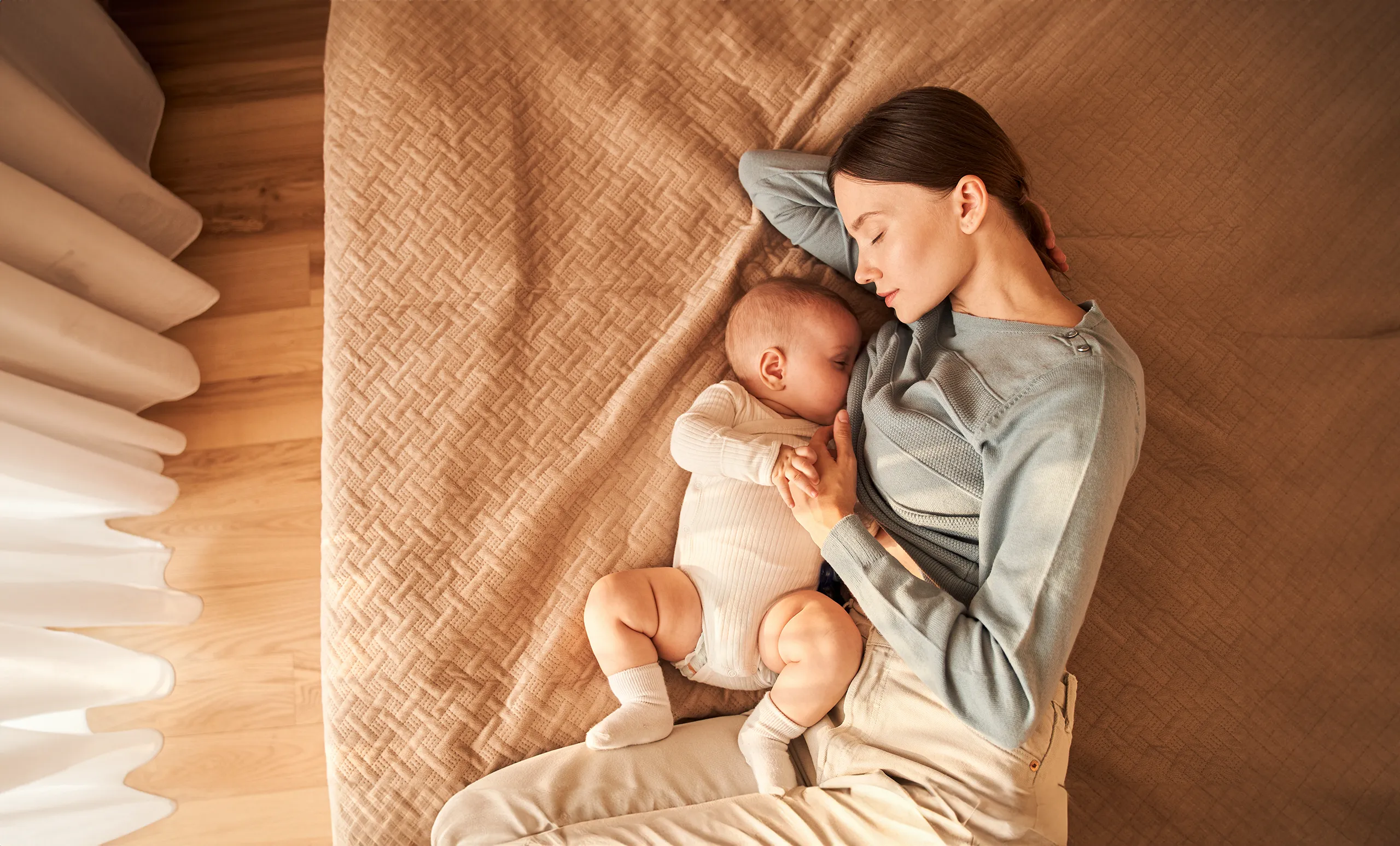 New mom laying in bed next to her newborn baby.