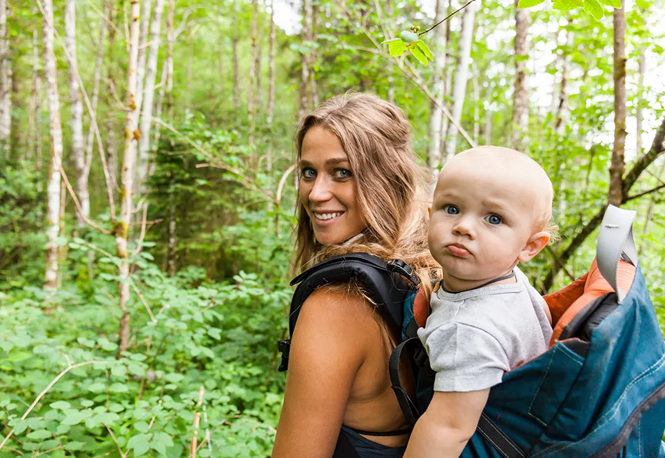 Blonde, caucasian mother going for a hike with a baby strapped to her back.