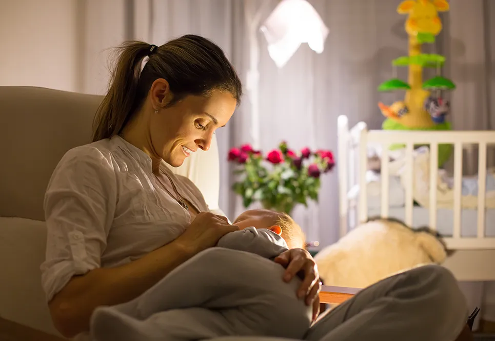 Mother attending to baby in the early evening, with dim lights all around.