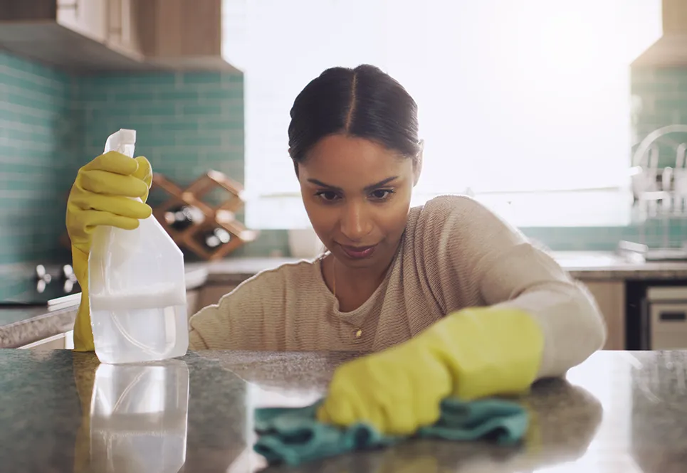 Young, latina mom cleaning the surface of her kitchen counter.