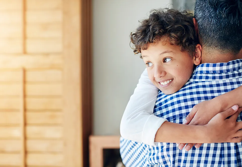 Father hugging his young child, while avoiding their face. 