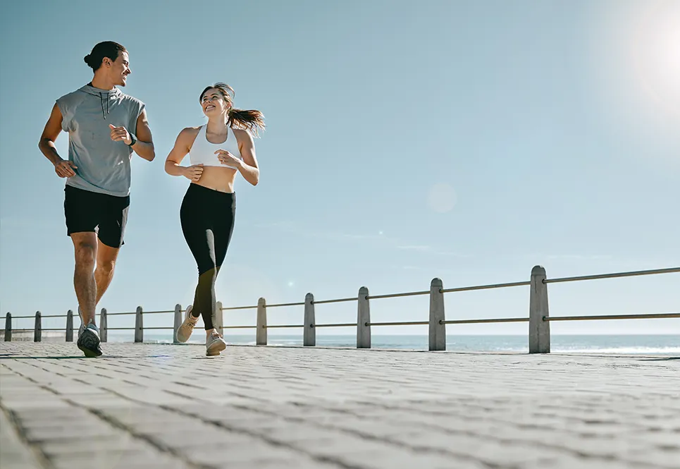 Young father and mother going for a run by the beach. 