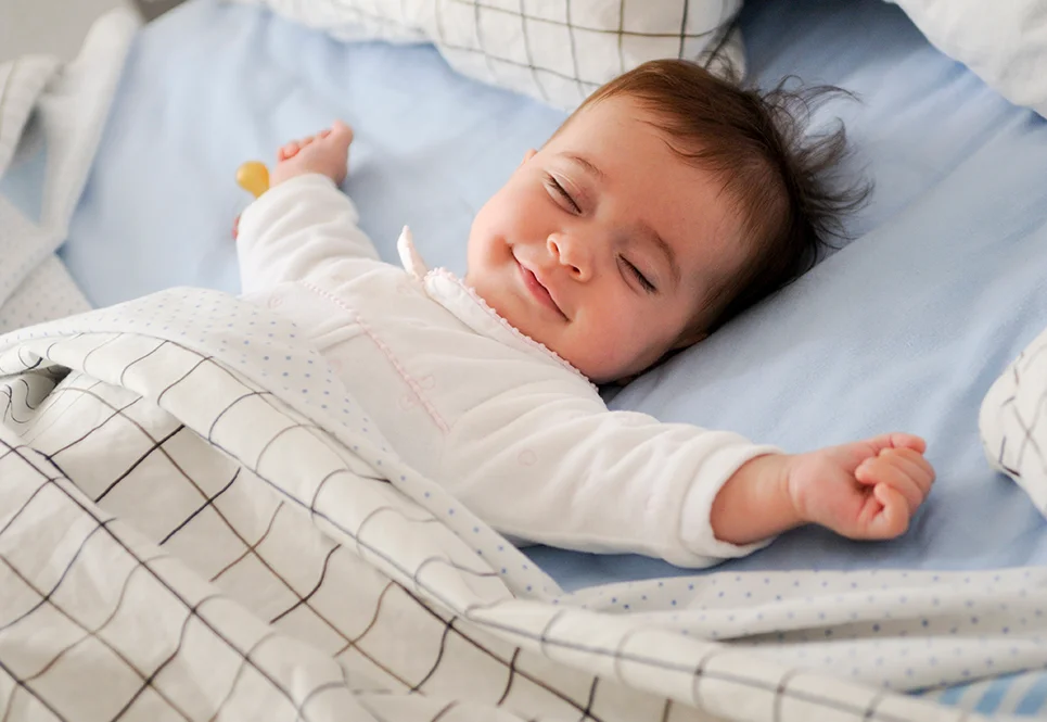 Peaceful, smiling caucasian baby sleeping on her back.