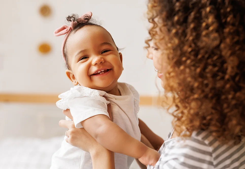 Smiling mixed race baby being held up by her mom.