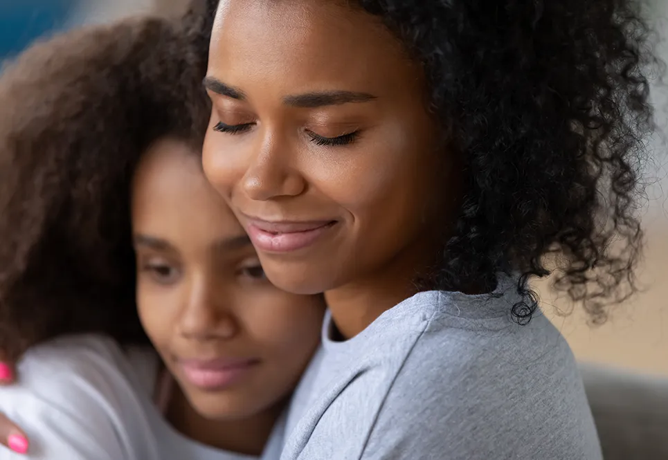 Young Black mom hugging sad teen daughter