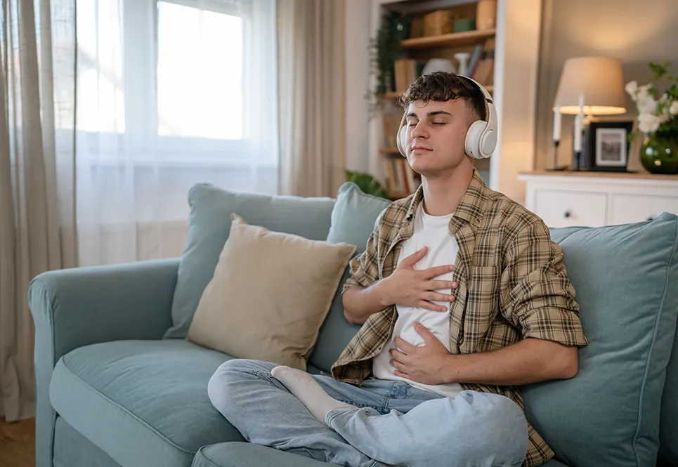 Teen boy practicing meditation on couch at home