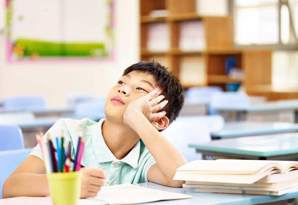 Asian boy daydreaming at school