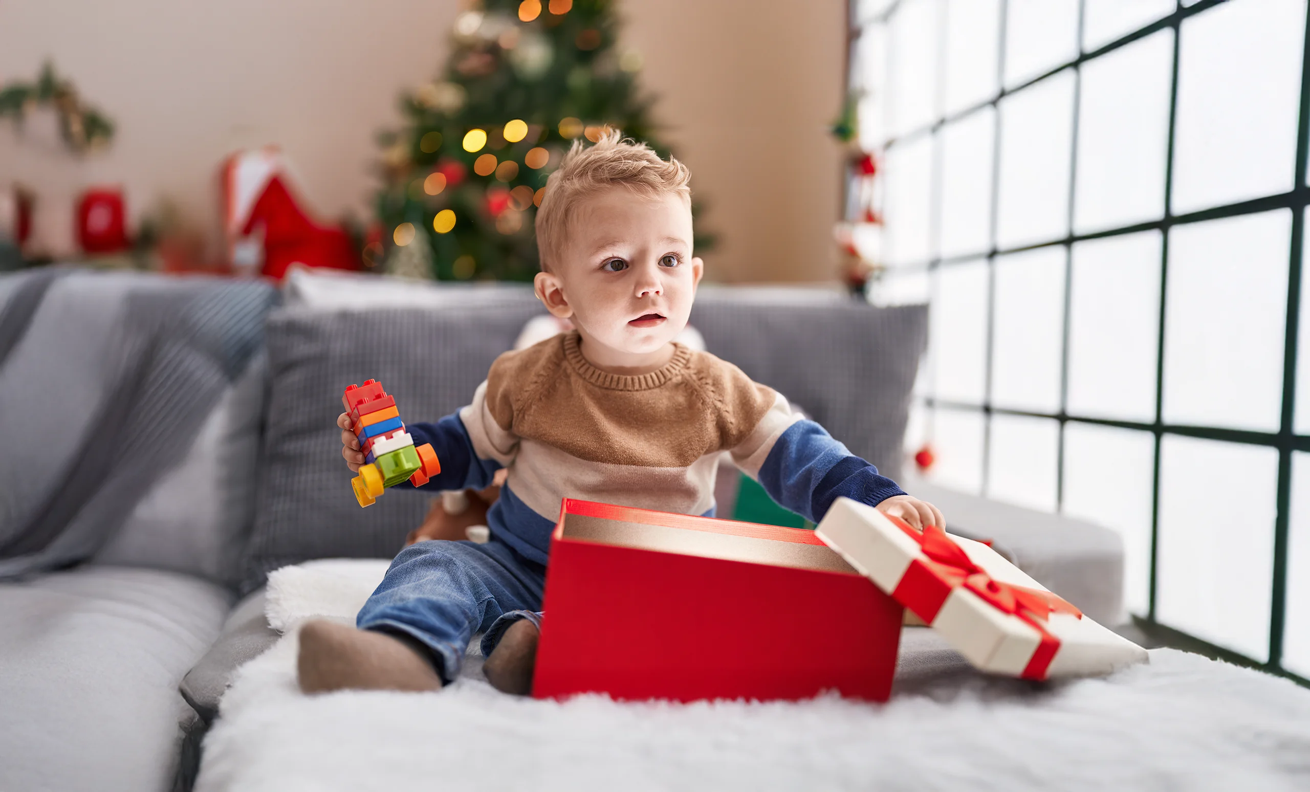 Caucasian toddler boy opening a gift at Christmas time