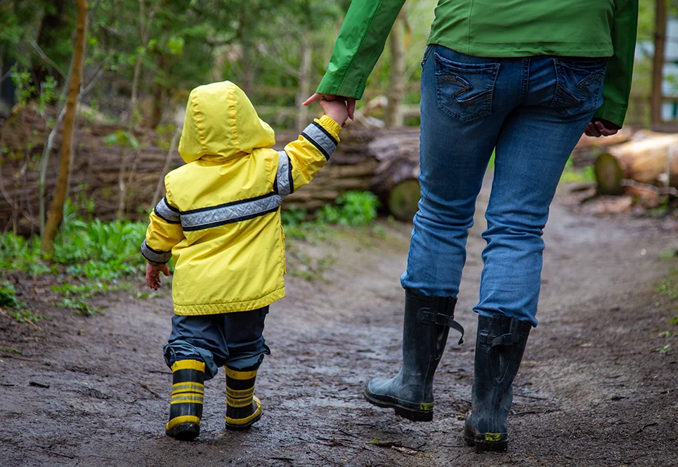 Young mom with her young toddler son going for a walk outside. 