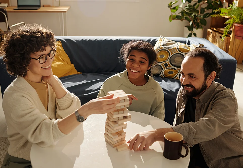 Smiling mother, father and teen playing Jenga. 