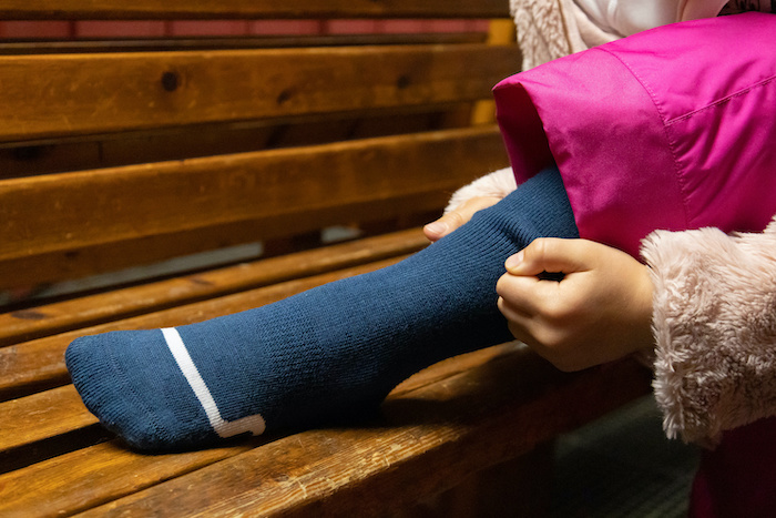 Young girl putting on warm ski and snowboarding socks. 