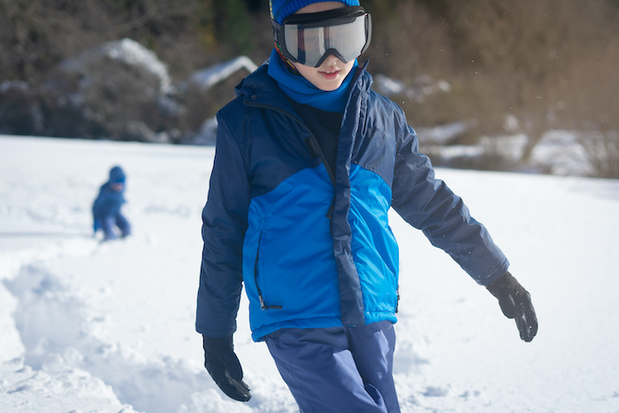 Teenage boy wearing warm winter skiing gear on a mountain. 