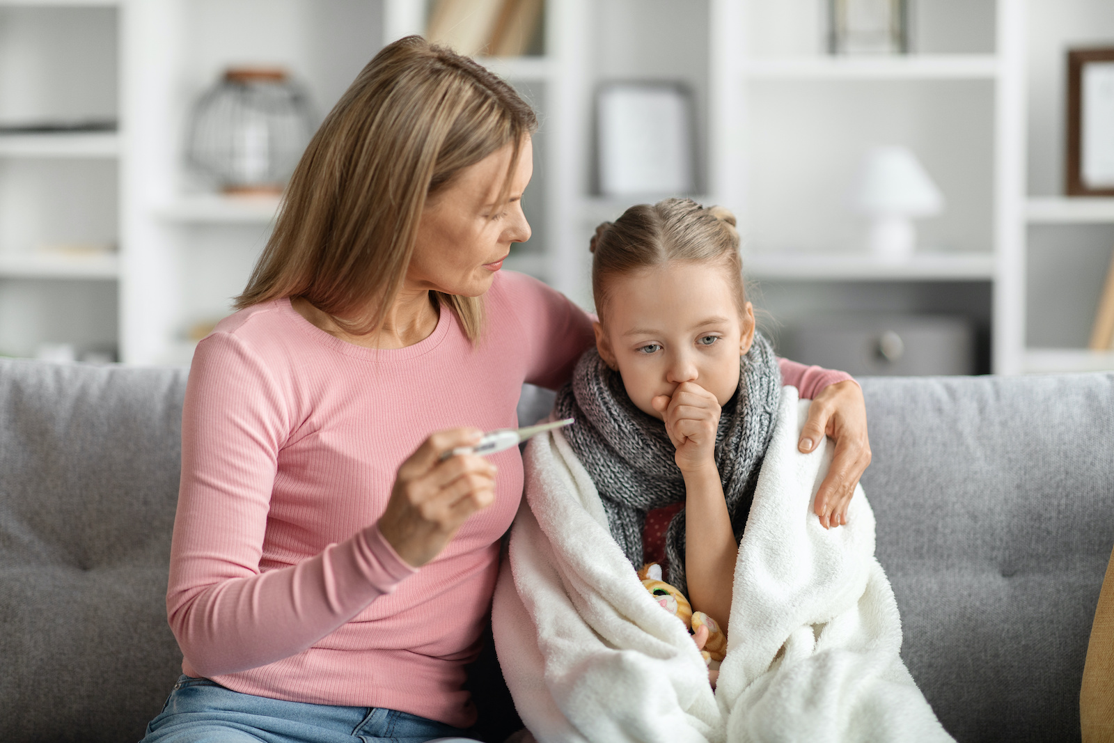 Blonde mom taking her sick daughter’s temperature