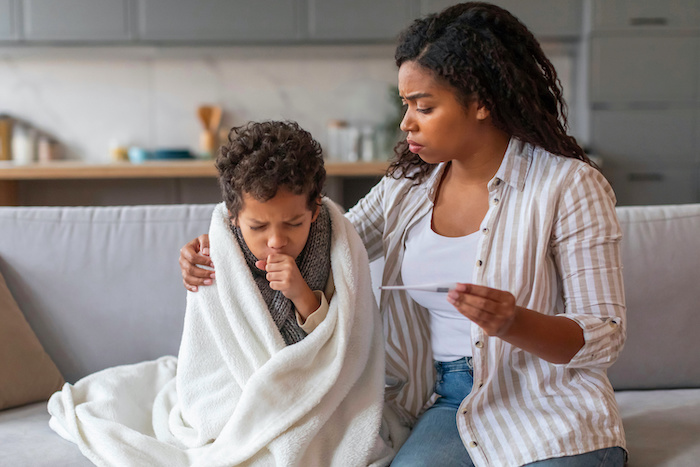 Young Black mom taking her sick son’s temperature 