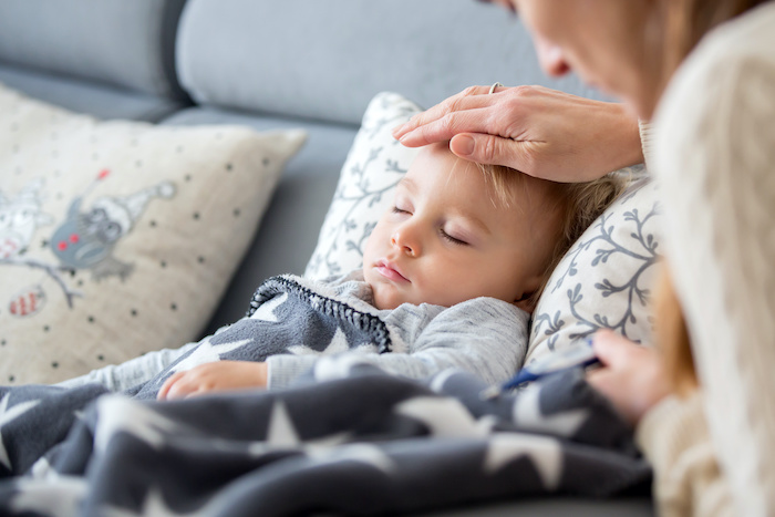 Mom comforting her sick, sleeping toddler