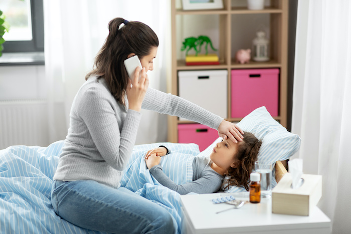 Ethnically ambiguous mom calling a pediatrician for her sick daughter