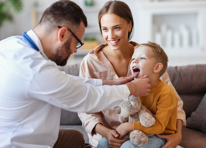 Male pediatrician examining a young caucasian boy on his mother’s lap