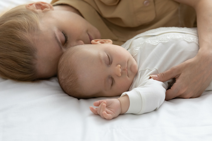 New mom getting sleep with her newborn baby. 