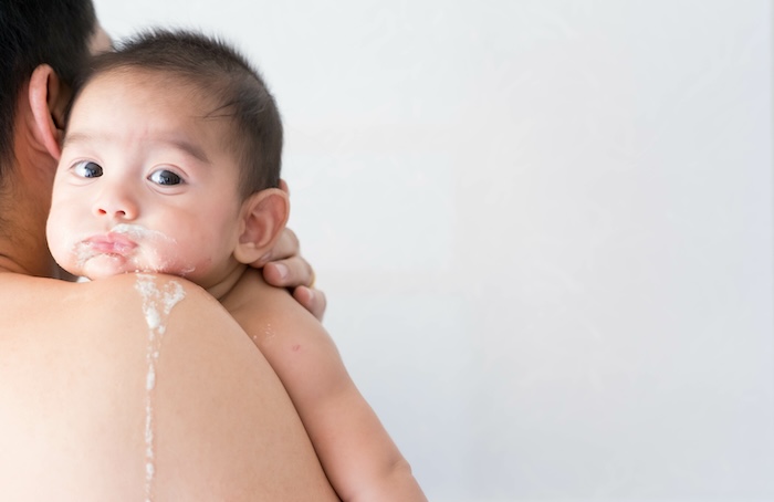 Young baby burping and spitting up baby formula. 
