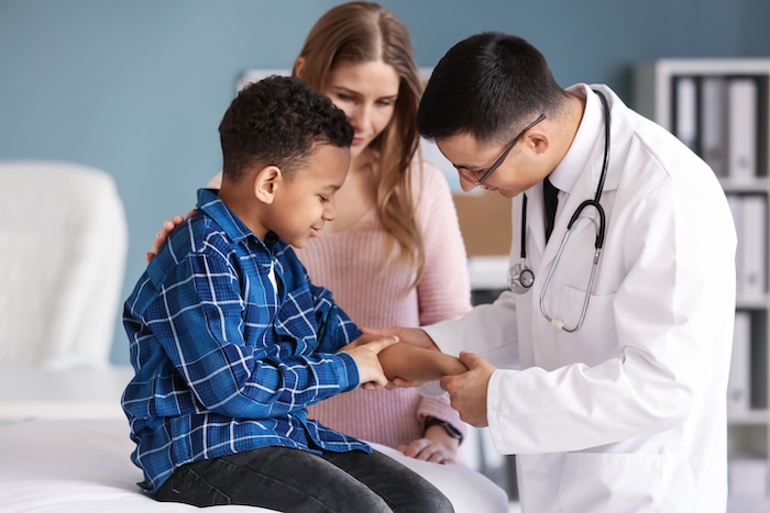 Pediatrician examining the arm of an ethically ambiguous pre-teen boy patient