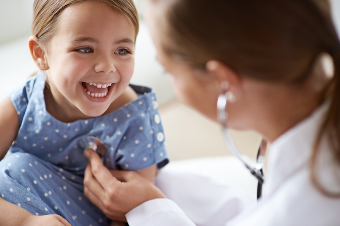 Female pediatrician checking a little girl with a stethoscope