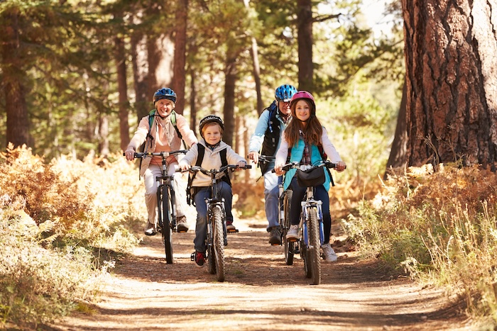 Family pedaling through a wooded area
