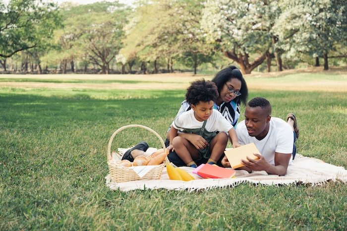 Family having a picnic at a large park.