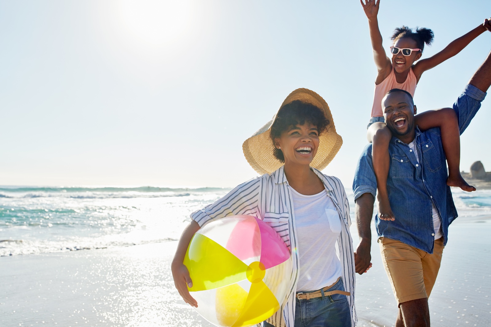 Young Smiling black family playing at the beach in Orange County.