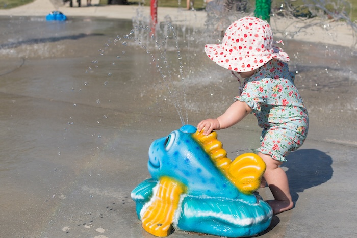 Young child wearing full body coverage clothing at an outdoor playground.