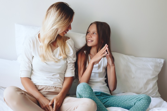 Blonde haired mother talking with her teen on a couch. 