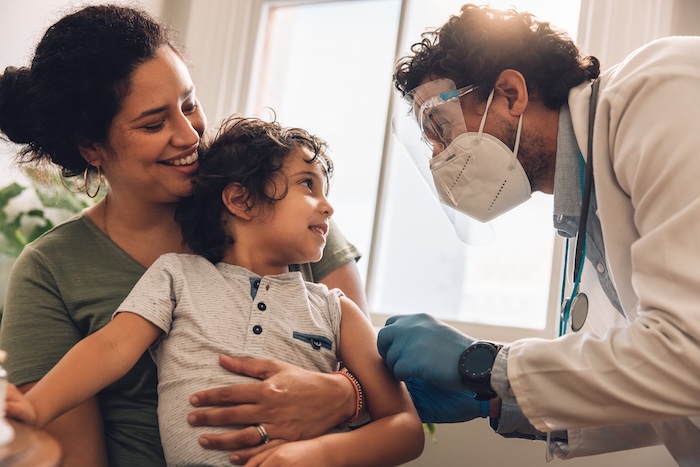 Closeup of pediatrician delivering a vaccine to a young child. 