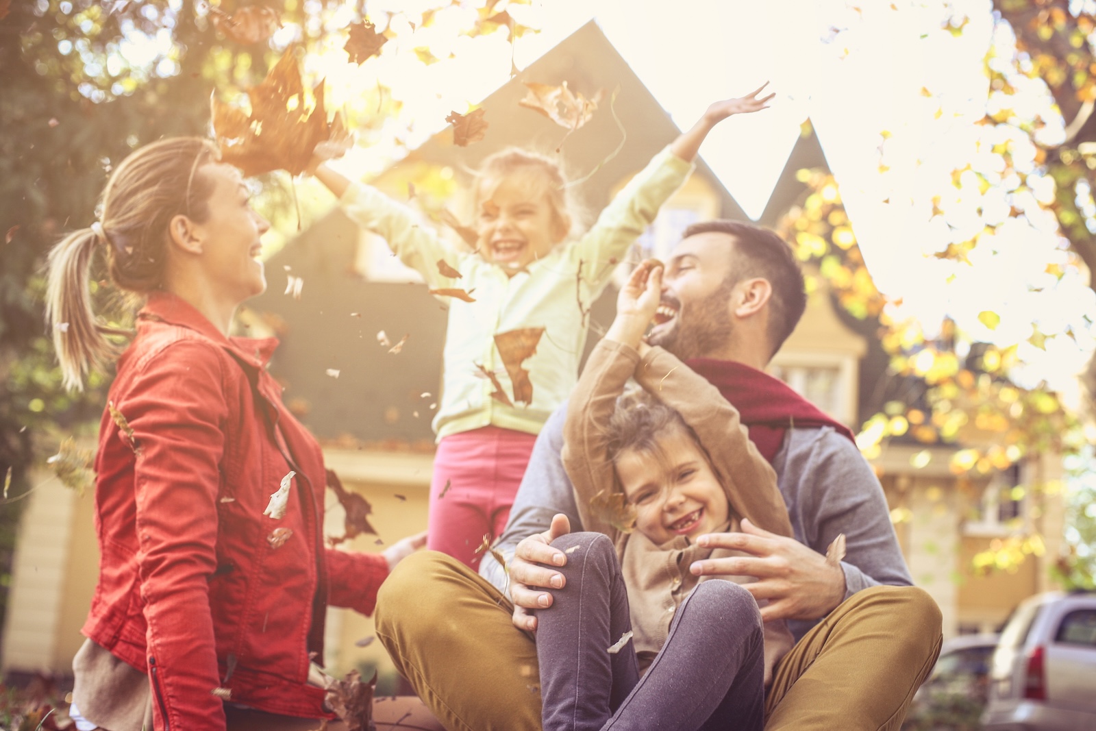 miling family in the front yard of their house during the fall