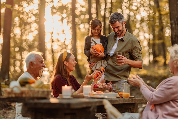 Happy family having an outdoor picnic in a park during the fall. 