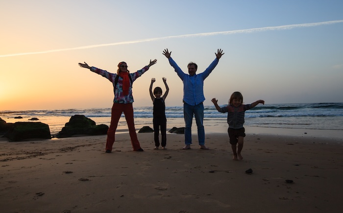 Family jumping up and down at the beach at sunset. 