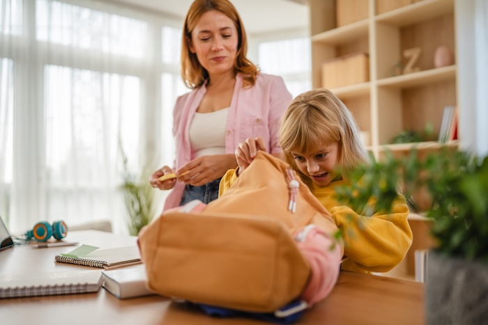 Parent packing an emergency fire supplies bag with their child. 