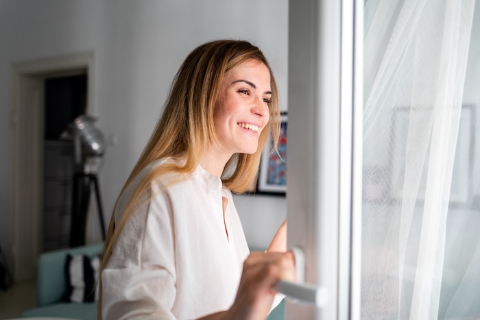 Woman opening up the windows in her home. 