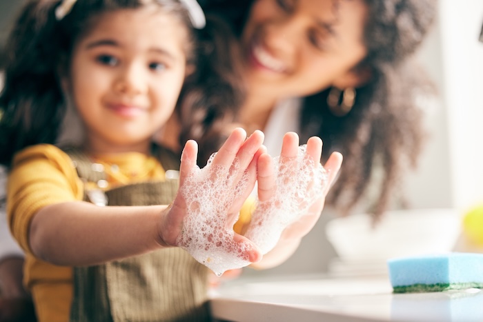 Closeup shot of young girl washing her hands with her mother. 