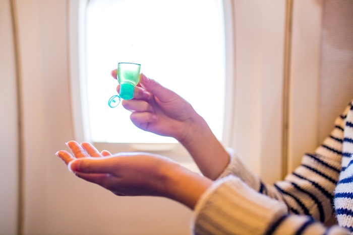 Mother using hand sanitizer in an airplane.
