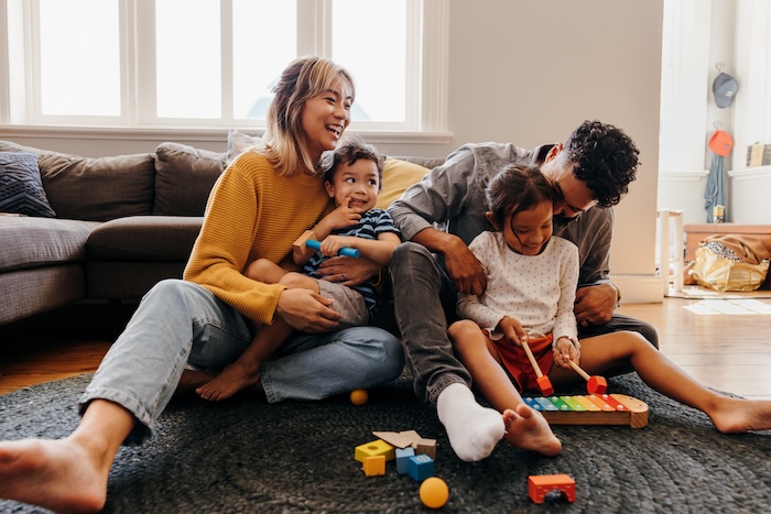 Mixed race family with two young kids playing together at home