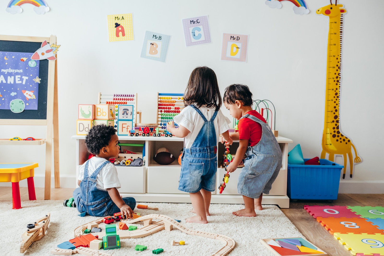 Three ethnically ambiguous toddlers playing in a colorful play space