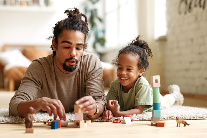 Black father and young son playing with wooden blocks at home