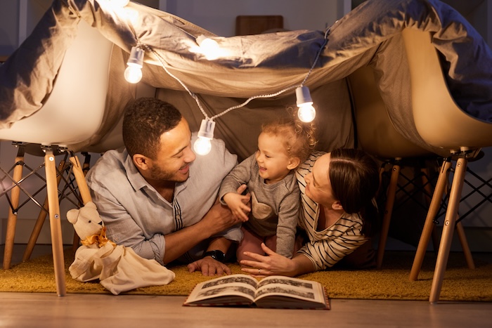 Ethnically ambiguous family with a toddler playing inside a pillow fort