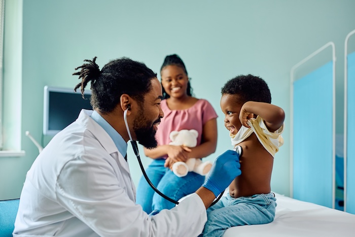 Black male doctor with a stethoscope checking the health of a little boy