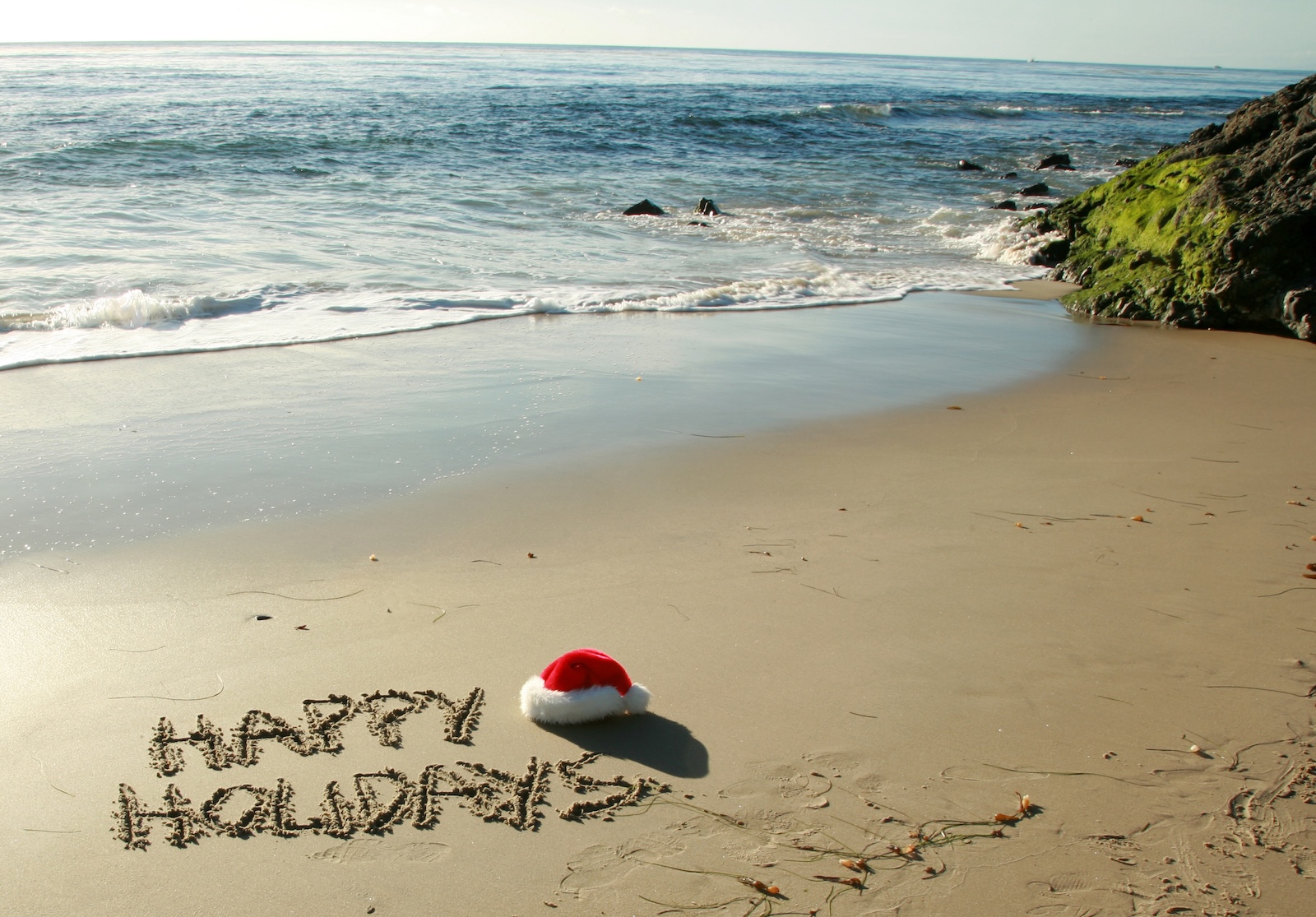 Happy Holidays written in sand at the beach.