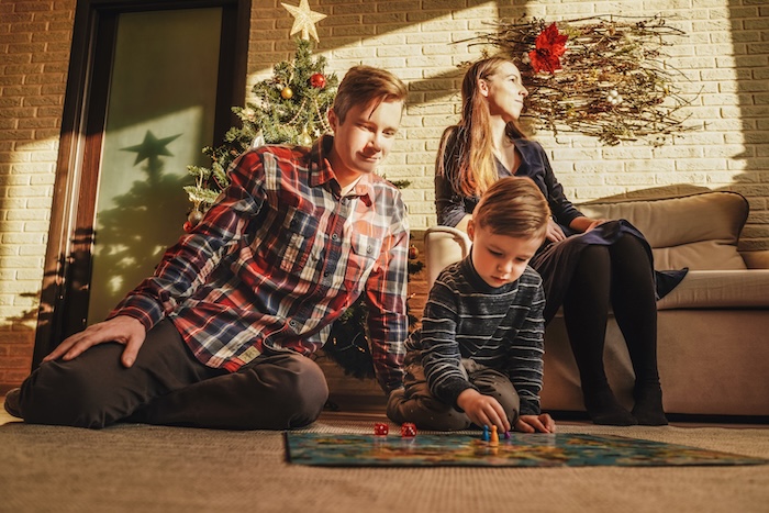 Family of three playing a board game during Christmas time