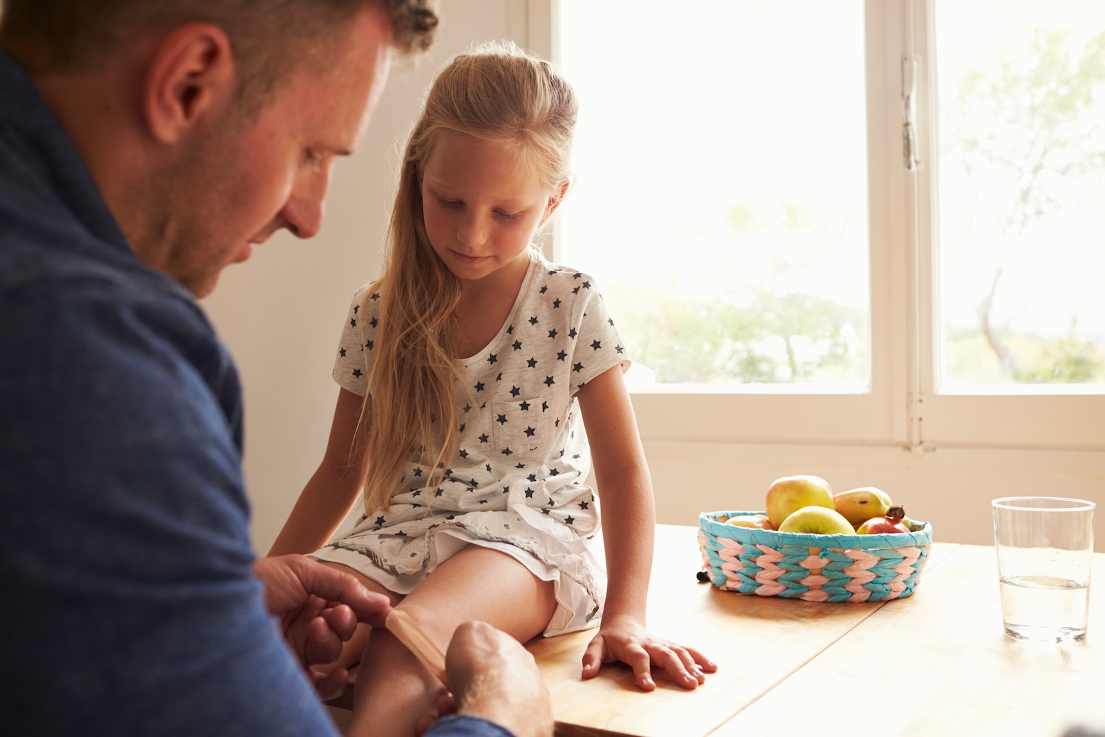 Young father treating a minor wound on his daughter’s knee.