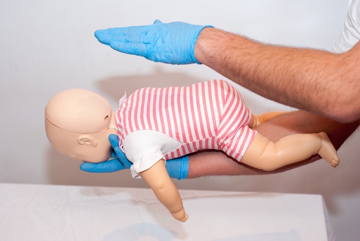 Person performing the heimlich on a child dummy in a course. 